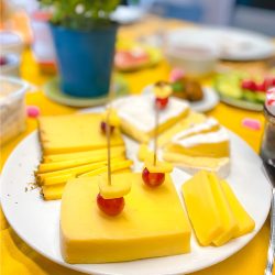 Ein Teller mit Käse und Obst auf einem gelben Tisch.