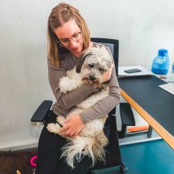 Eine Frau hält einen Hund auf einem Bürostuhl.