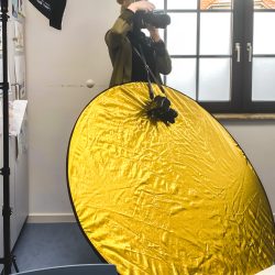Eine Frau macht ein Foto mit einem gelben Reflektor.